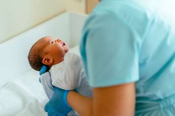 Health-care provider holding newborn baby in front of them