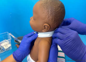 With the child in a sitting position and the tracheostomy tube is held in place the ties are secured on either side of the neck