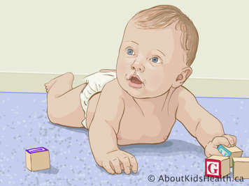 Baby lying on the floor on their tummy, playing with blocks