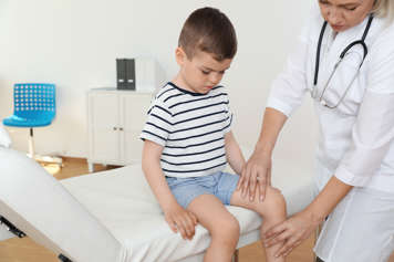 Child having their knee and lower leg examined by a health-care provider