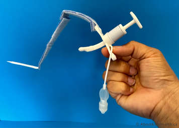 Inspecting clean tracheostomy tube to make sure it is not bent, cracked or discoloured