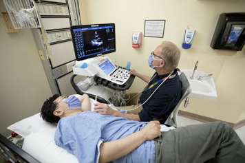 Sonographer doing echocardiogram ultrasound in echo room on patient