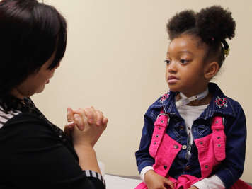 Caregiver speaking to child with a tracheostomy.