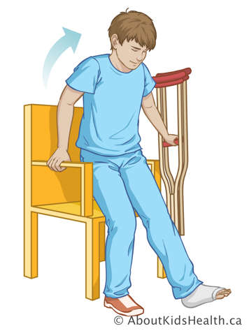 Boy getting up from a chair with the support of both crutches together on one side and one arm of the chair on the other