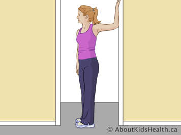 Woman standing sideways in doorframe with one arm, bent at the elbow, held up against the frame behind her