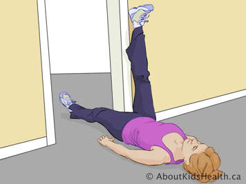 Femme allongée sur son dos devant une porte avec une jambe étendue sur le mur et l’autre étendue en travers de la porte