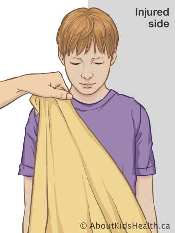 Holding triangular bandage at one corner up to child’s shoulder on uninjured side