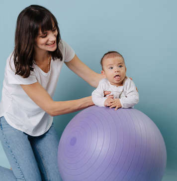 Mother with baby showing tummy time on an exercise ball