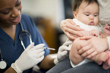 Parent holding infant in upright position before needle poke