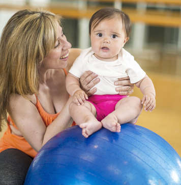 Mother with baby showing sitting on an exercise ball
