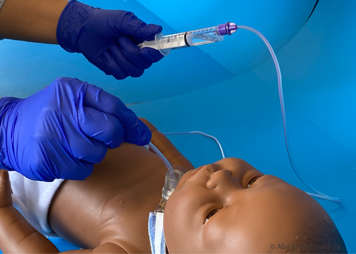 Drawing back on syringe that is attached to feeding tube that is being used to manually suction child