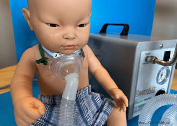 Mist coming through tracheostomy mask that has been placed over tracheostomy on a child