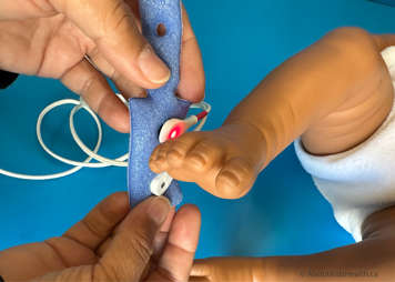 A reusable Y-sensor probe with foam wrap being lined up on a baby's foot