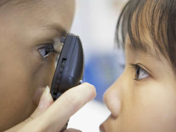 An optometrist looks into a patient’s eye
