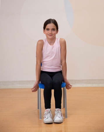 girl sitting in chair with shoulders rolled forward