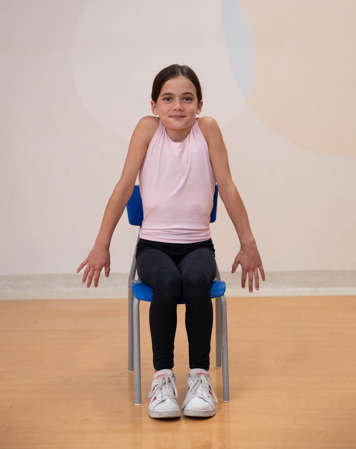 girl sitting in chair with shoulders pulled up under her ears