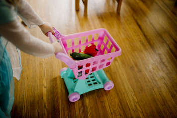 Child pushing toy shopping cart
