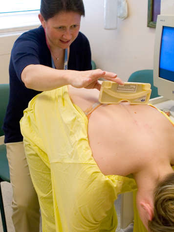 Nurse measuring curve of teen girl back