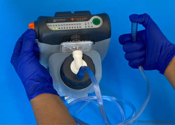 Suction device showing a thumb over the end of the suction tube and the pressure being adjusted with the other hand