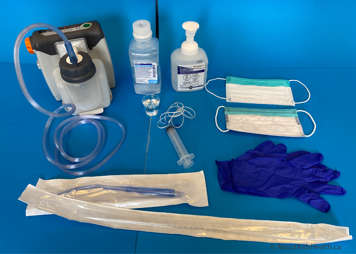 Supplies for tracheostomy suctioning - a manual syringe, suction catheters and tubing, a suction machine, saline nebules and a mask and gloves to protect the caregiver from droplets