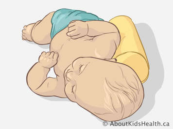 Baby lying on their side, supported by a crib roll behind the back.