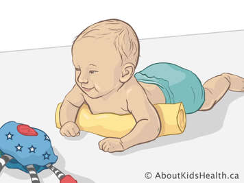 Bébé jouant sur le plancher sur son ventre avec un coussin sous la poitrine