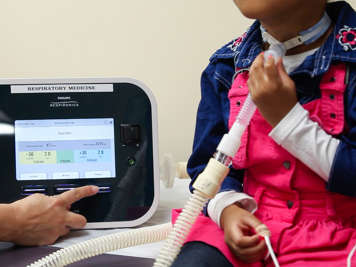 A child using a cough assist machine with a tracheostomy adapter