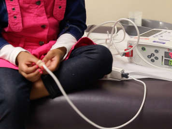 Child wearing oximeter probe on thumb.