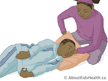 Caregiver placing a pillow under a child's head while keeping the child on their side